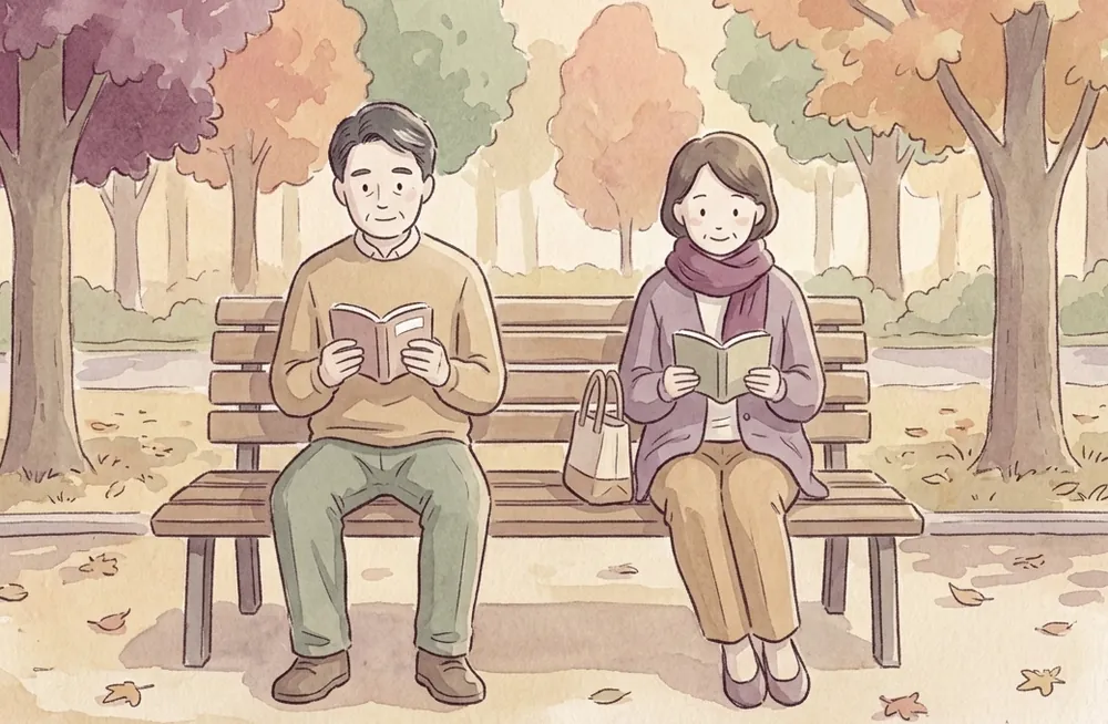公園のベンチで程よい距離を保って本を読む二人